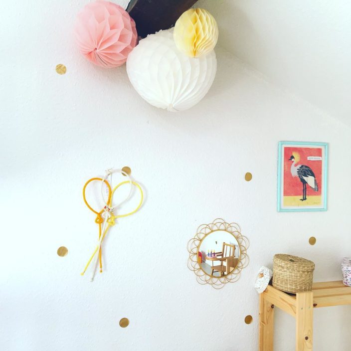 Chambre de fille décorée de point dorée sur les murs, trio de ballon accroché au mur et entouré d'un cadre et miroir ainsi que de jolis boules chinoises en papier viennent habiller le plafond.
